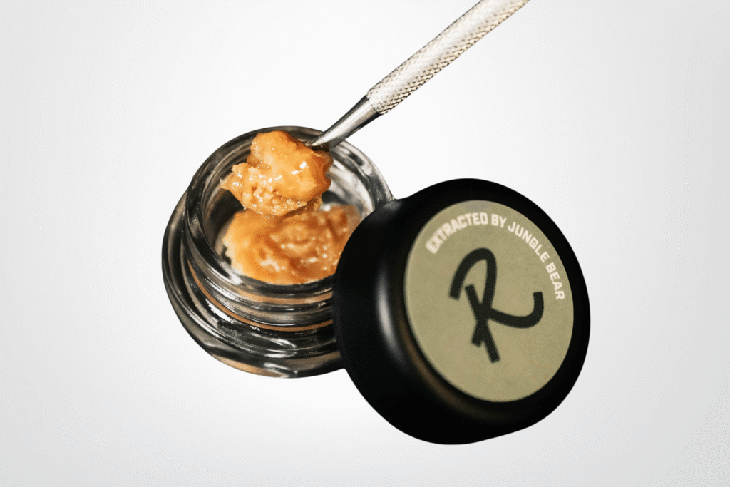 Live Hash Rosin by Revival: Farm.Lab.Market, extracted by Jungle Bear, with a metal dab tool lifting creamy golden rosin from an open jar.