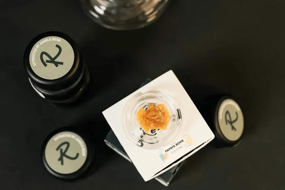 Papaya Bomb Live Rosin, an indica-leaning hybrid, shown in an open jar with creamy golden texture, highlighting its tropical and floral aroma, smooth consistency, and solventless, cold-cured production